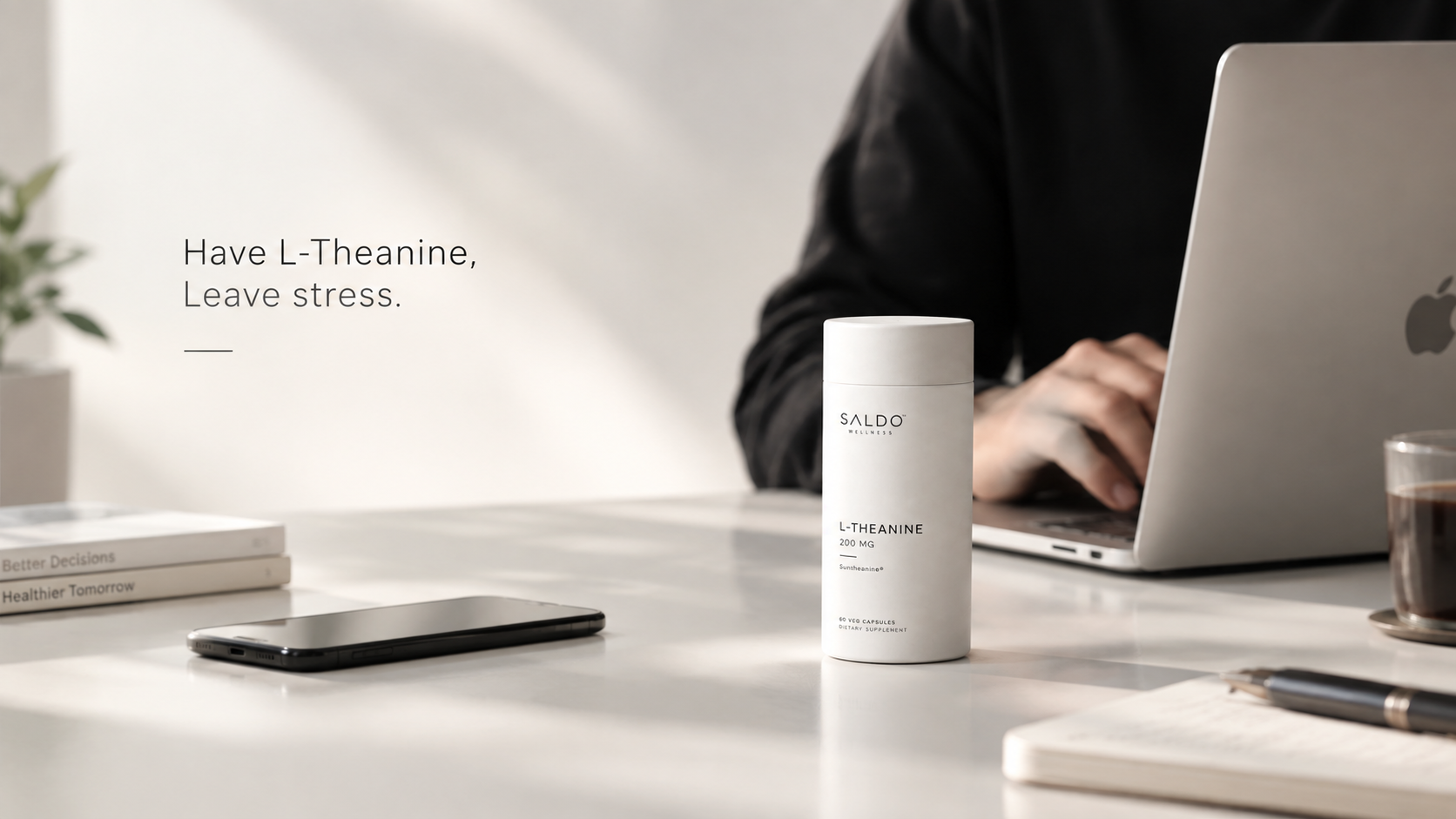 A person working at a laptop with a Saldo Wellness L-Theanine bottle on the desk